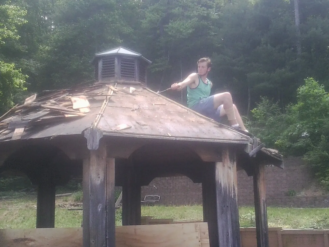 Tearing the old roof off a wooden gazebo before new shakes in Gotha