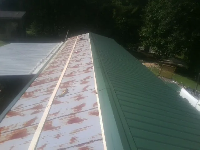Old rusted panels beside newly installed green metal roofing — Wind Damage Roof Repair by Roofing Brothers in Gotha