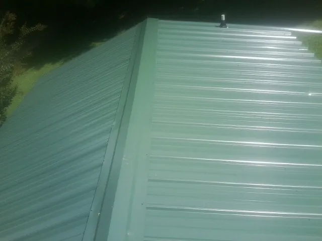 New green metal panels meeting at the ridge of a roof — Flat Roof Repair work by our crew in Gotha