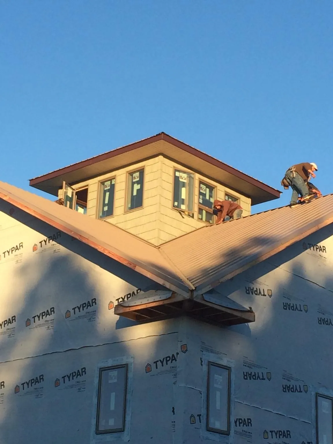 Roofers working around a rooftop cupola on a new metal roof at sunset — Roof Waterproofing in Gotha by Roofing Brothers